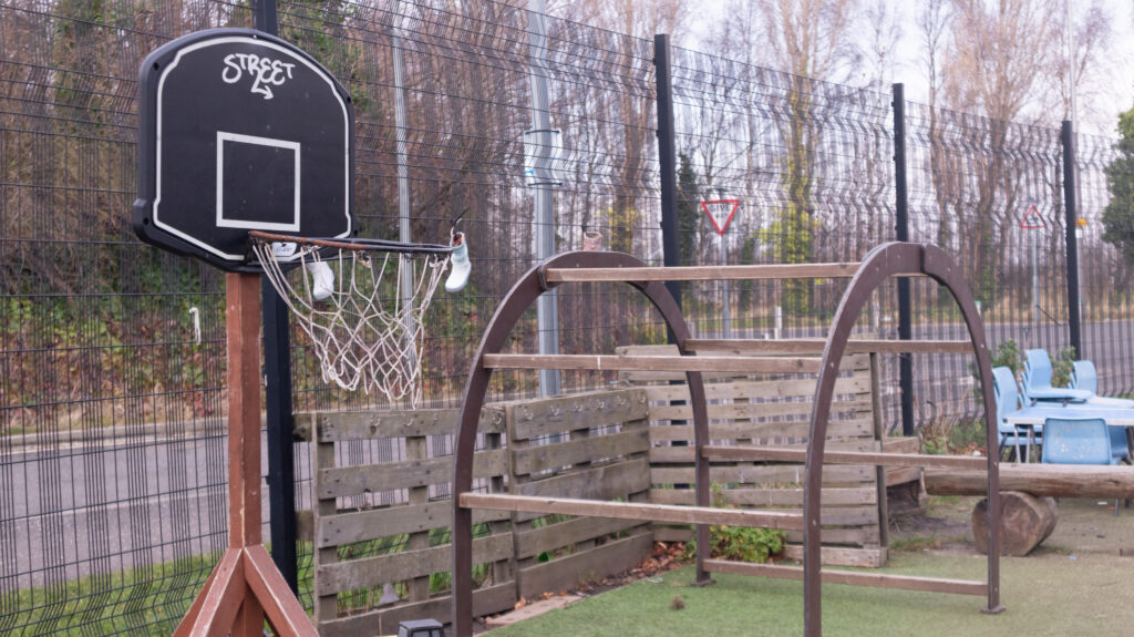 Close-up of the outdoor play area of the nursery showing the basketball hoop and seating.